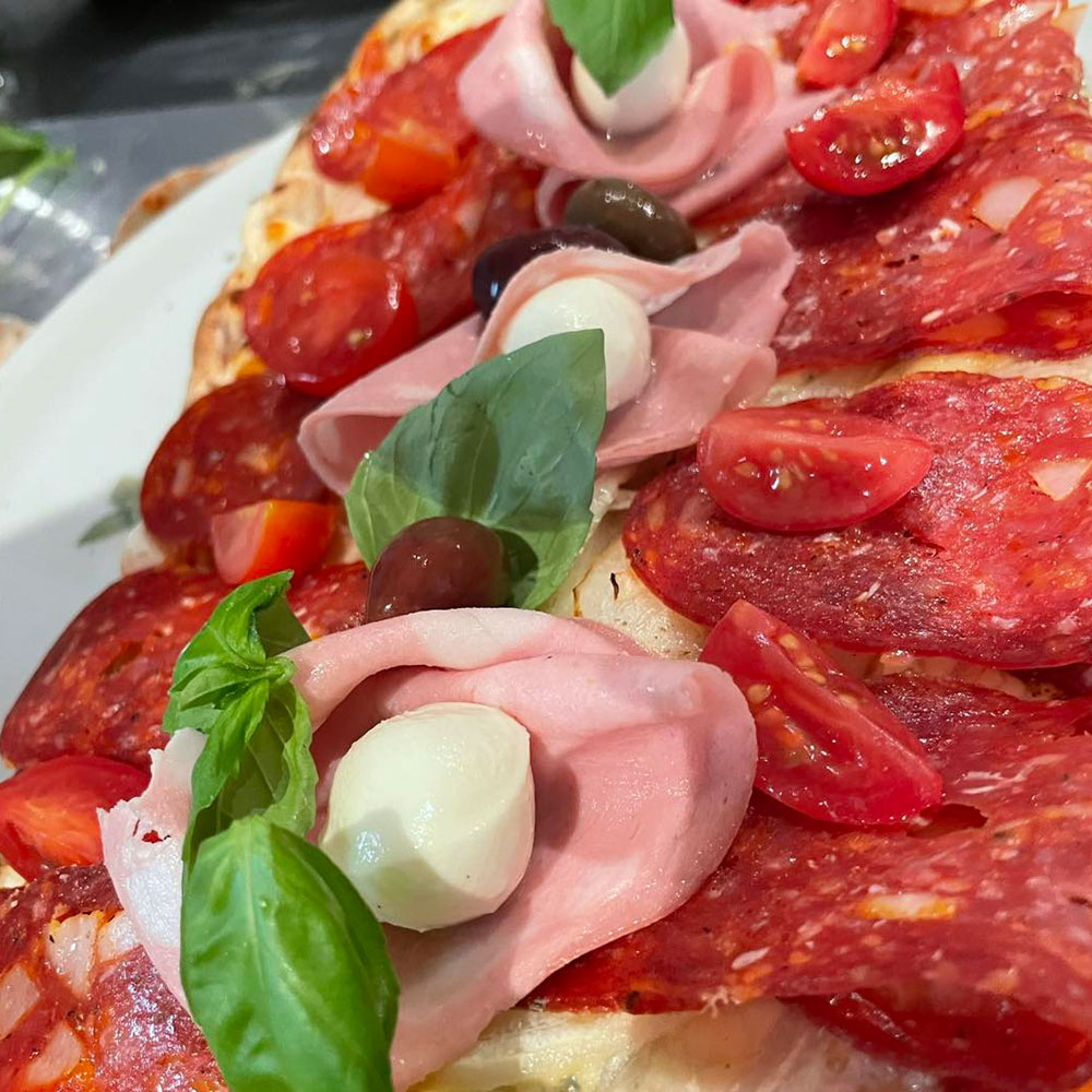 Pizza mit Salami piccante Mortardella und Tomaten